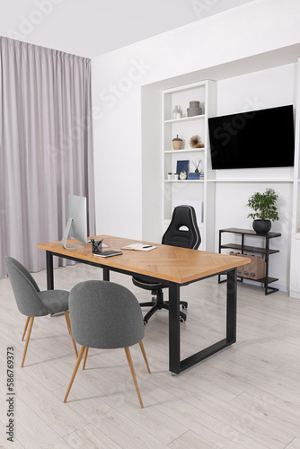 Stylish director's workplace with wooden table, tv zone and comfortable armchairs in office. Interior design © New Africa
