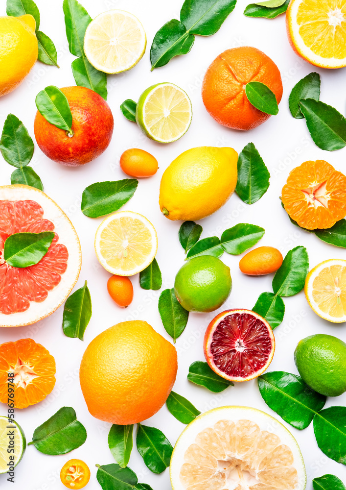 Citrus fruit food background, top view. Mix of different whole and sliced fruits: orange, grapefruit, lime and other with leaves on white table Citrus fruit food background, top view. Mix of different whole and sliced fruits: orange, grapefruit, lime and other with leaves on white table