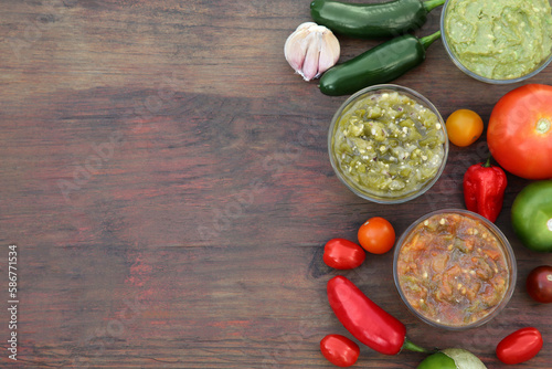 Tasty salsa sauces and ingredients on wooden table, flat lay. Space for text