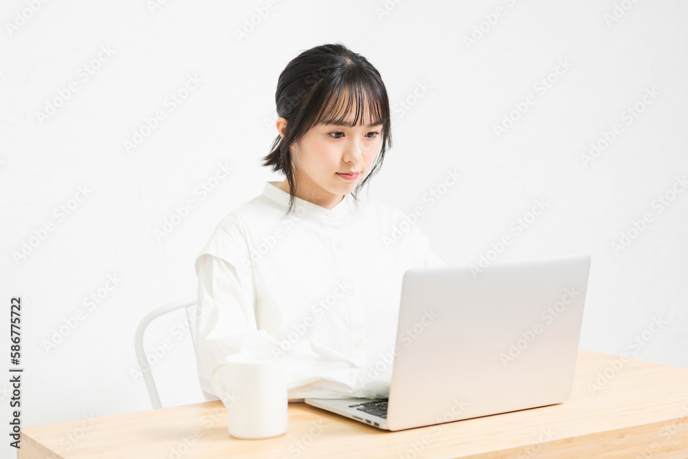 白背景の前でPCを操作する若い女性 白背景の前でPCを操作する若い女性
