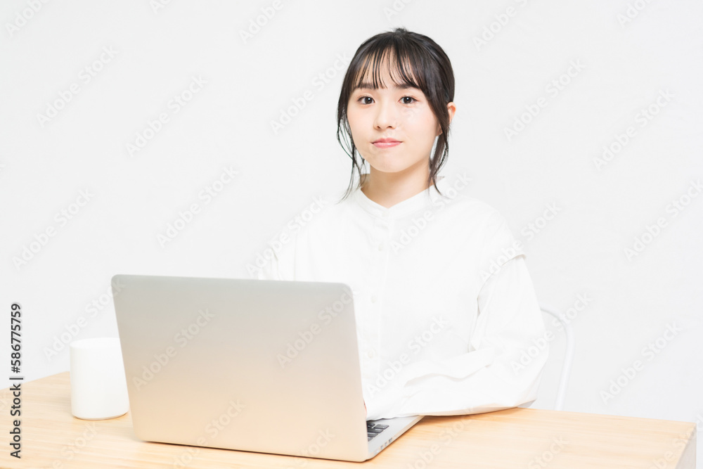 白背景の前でPCを操作する若い女性 白背景の前でPCを操作する若い女性