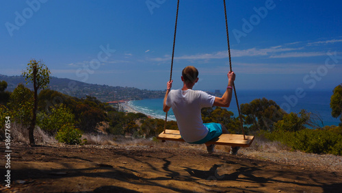 Young man on swing with beautiful beach views