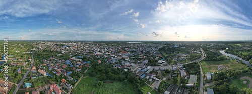 Panoramic of the view of the city from a distance, with the greenery and blue sky in the foreground offers a sense of perspective and balance.