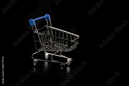 Miniature metal shopping trolley from a supermarket on a black background