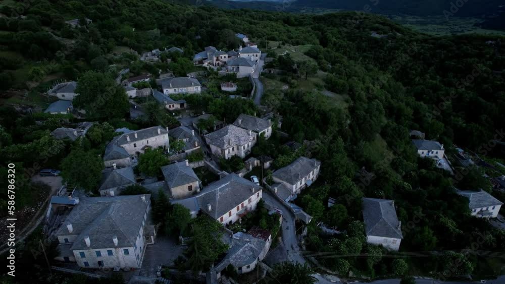 Aerial view of small rural village with several houses on the slope of green Tymfi mountain after sunset Aerial view of small rural village with several houses on the slope of green Tymfi mountain after sunset