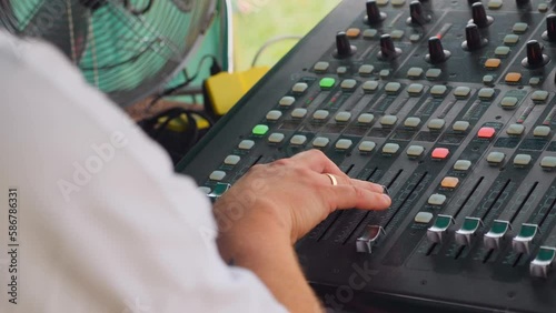 Sound engineer sliding potentiometers up, slow motion 50 fps photo