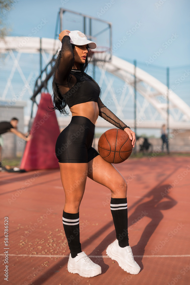 Sporty girl fitness model posing on basketball court 