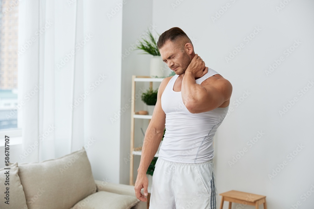 Man sports neck and back pain after working out at home, the concept of health and body beauty Man sports neck and back pain after working out at home, the concept of health and body beauty