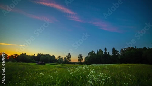 Beautiful meadow flower field midnight sun timelapse with rare silver noctilucent clouds illuminated by sun. Sunset to sunrise evening morning time lapse conceptn photo