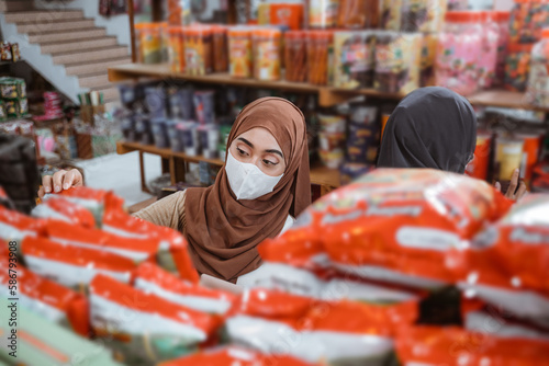 Muslim girl in mask choosing items while shopping in store