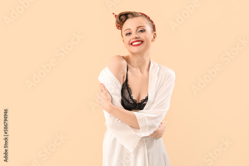 Young pin-up woman in dressing gown on beige background © Pixel-Shot