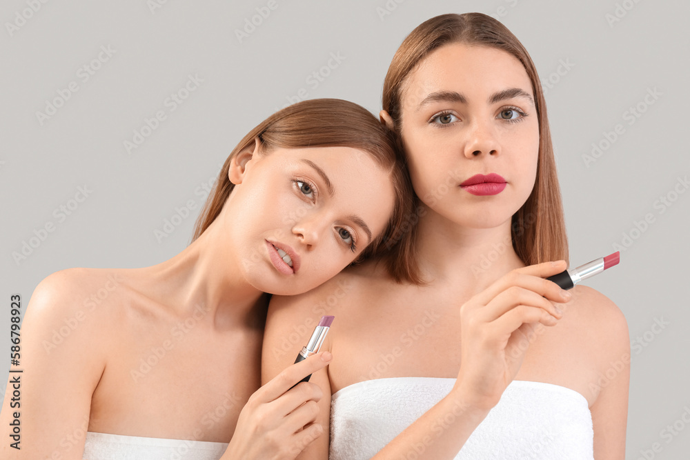 Young women with lipsticks on grey background, closeup Young women with lipsticks on grey background, closeup