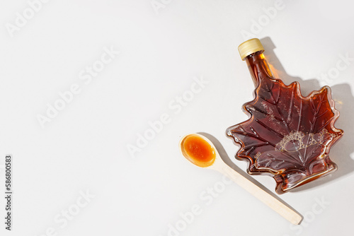 Foto Bottle and spoon of tasty maple syrup on grey background