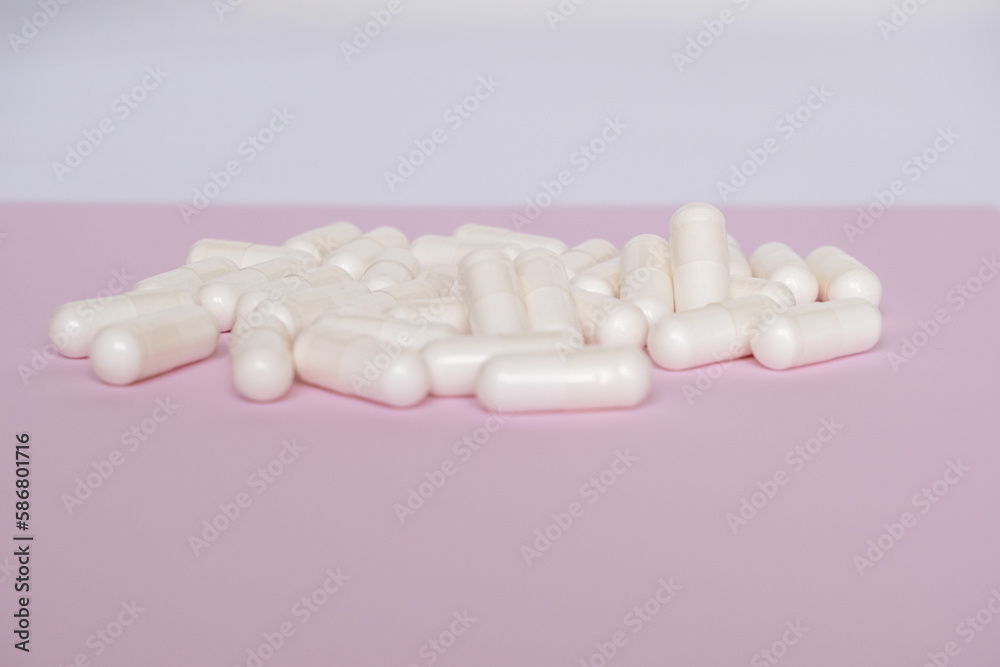 White capsules for digestion on a pale pink background. White capsules with space for text. White capsules for digestion on a pale pink background. White capsules with space for text.