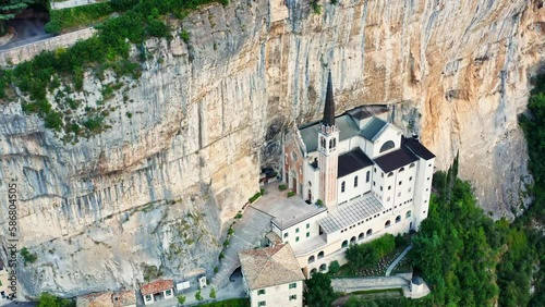 The aerial view of Madonna della Corona , Italy , during the morning golden hour displays the stunning mountaintop church perched precariously on a cliff, with the warm light.