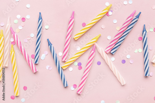 Colorful birthday candles and glitter on pink background