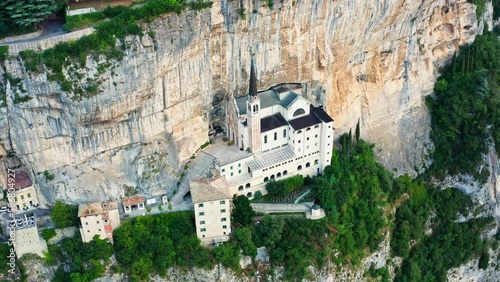The aerial view of Madonna della Corona , Italy , during the morning golden hour displays the stunning mountaintop church perched precariously on a cliff, with the warm light.