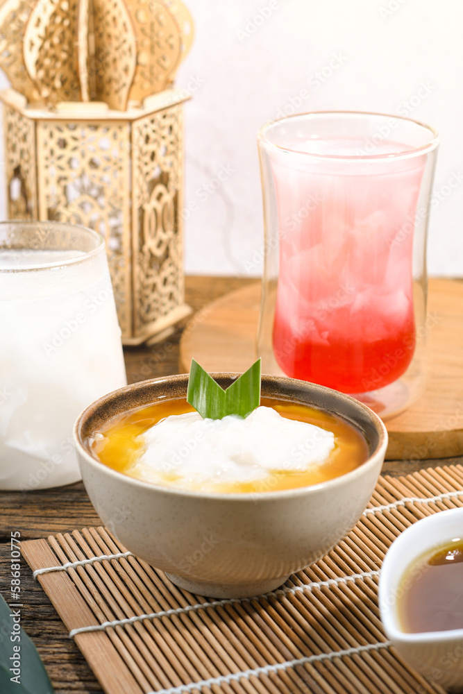 Bubur Sumsum served on wooden table, Javanese dessert porridge of rice flour, coconut milk with brown sugar syrup. A popular iftar food for breaking the fast Ramadan Bubur Sumsum served on wooden table, Javanese dessert porridge of rice flour, coconut milk with brown sugar syrup. A popular iftar food for breaking the fast Ramadan