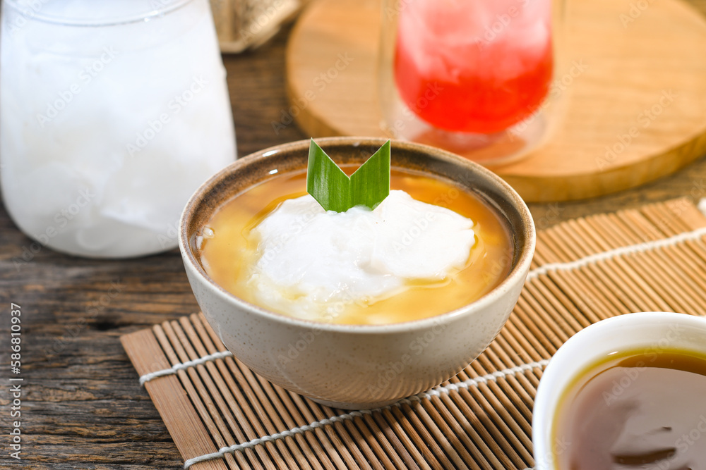 Bubur Sumsum served on wooden table, Javanese dessert porridge of rice flour, coconut milk with brown sugar syrup. A popular iftar food for breaking the fast Ramadan Bubur Sumsum served on wooden table, Javanese dessert porridge of rice flour, coconut milk with brown sugar syrup. A popular iftar food for breaking the fast Ramadan