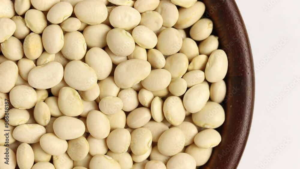 White kidney beans in wooden bowl rotating on white background, top view. White kidney beans in wooden bowl rotating on white background, top view.