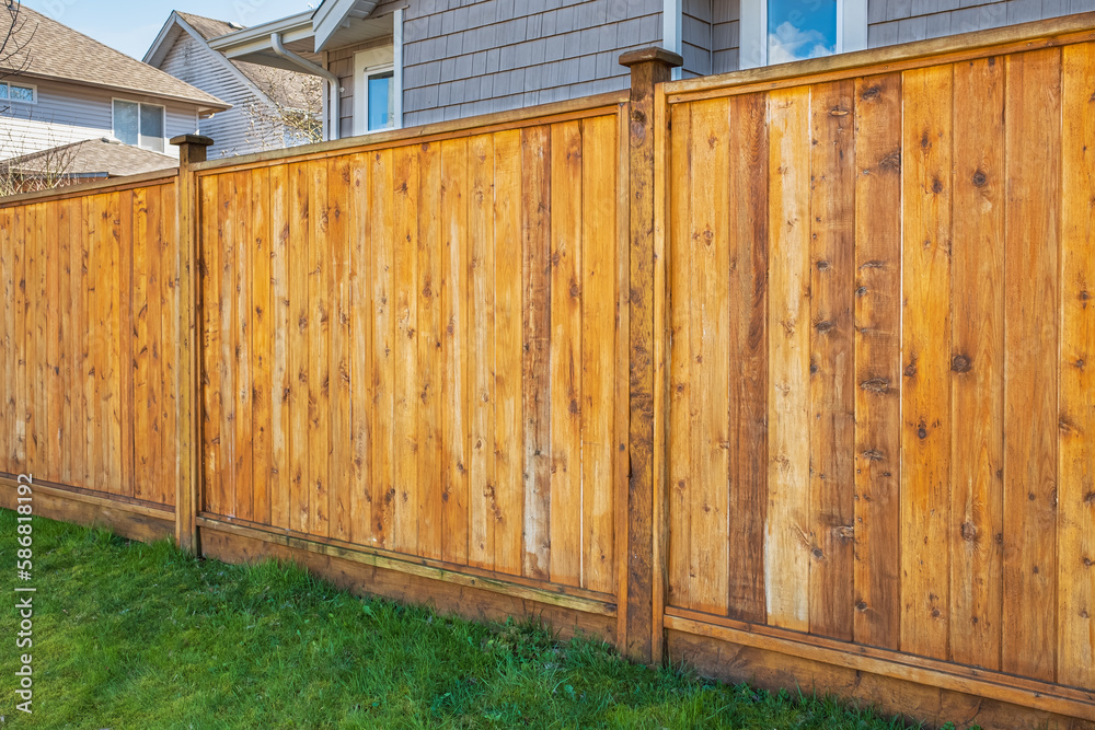 Nice new wooden fence around house. Wooden fence with green lawn. Street photo Nice new wooden fence around house. Wooden fence with green lawn. Street photo
