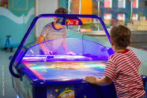 Boys play air hockey, entertainment center. Joyful brothers playing air hockey game at amusement park. close-up portrait. Arcade centre