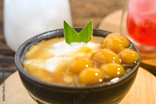 Bubur Sumsum Biji Salak or Candil Ubi served on wooden table, Indonesian traditional dessert porridge of rice flour, coconut milk with brown sugar syrup. Ramadhan iftar snack photo