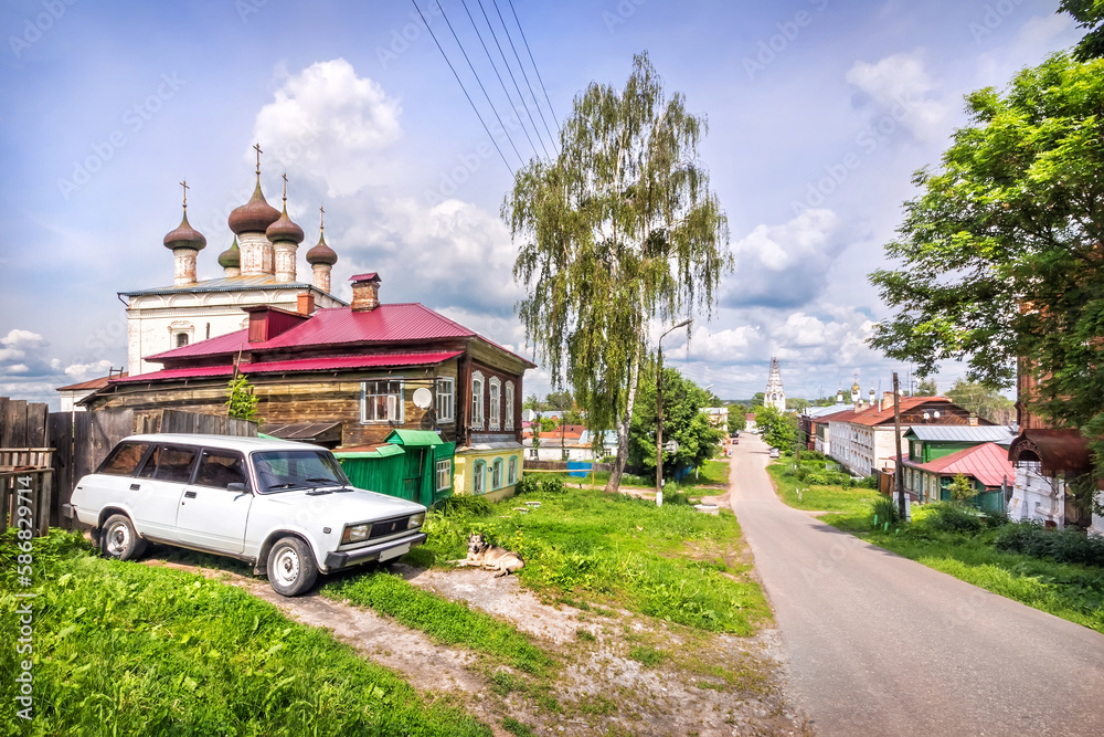 Domes of the Church of the Resurrection, village houses, a white car and a dog, Gorokhovets Domes of the Church of the Resurrection, village houses, a white car and a dog, Gorokhovets