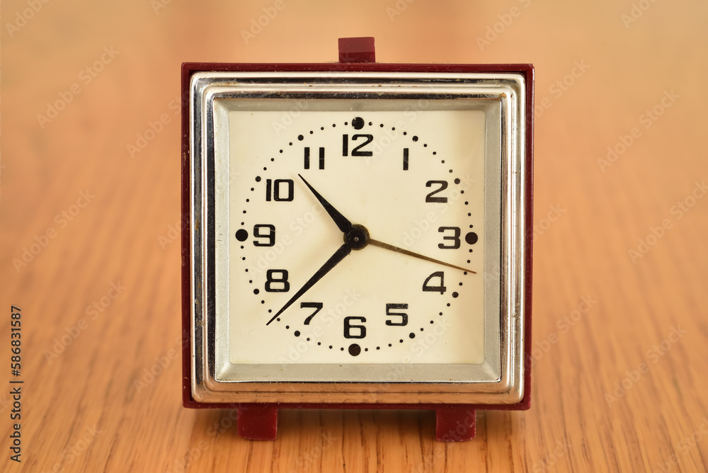 Old small clock on the brown wooden table. Close-up. Retro style photo. Old small clock on the brown wooden table. Close-up. Retro style photo.
