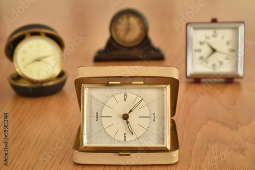 Old small clocks on the brown wooden table. Close-up. Selective focus. Retro style photo. 