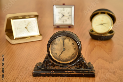 Old small clocks on the brown wooden table. Close-up. Selective focus. Retro style photo. 