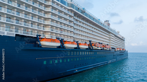 Safety equipment lifeboat. Orange lifeboat hanging over Sea on the side of a Cruise ship photo