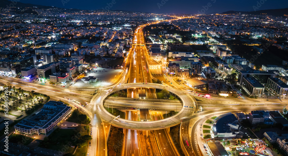 Obraz premium Aerial view of a illuminated multilevel junction ring road as seen in Attiki Odos toll road motorway interchange with Kifisias Avenue in Athens, Greece, during night time
