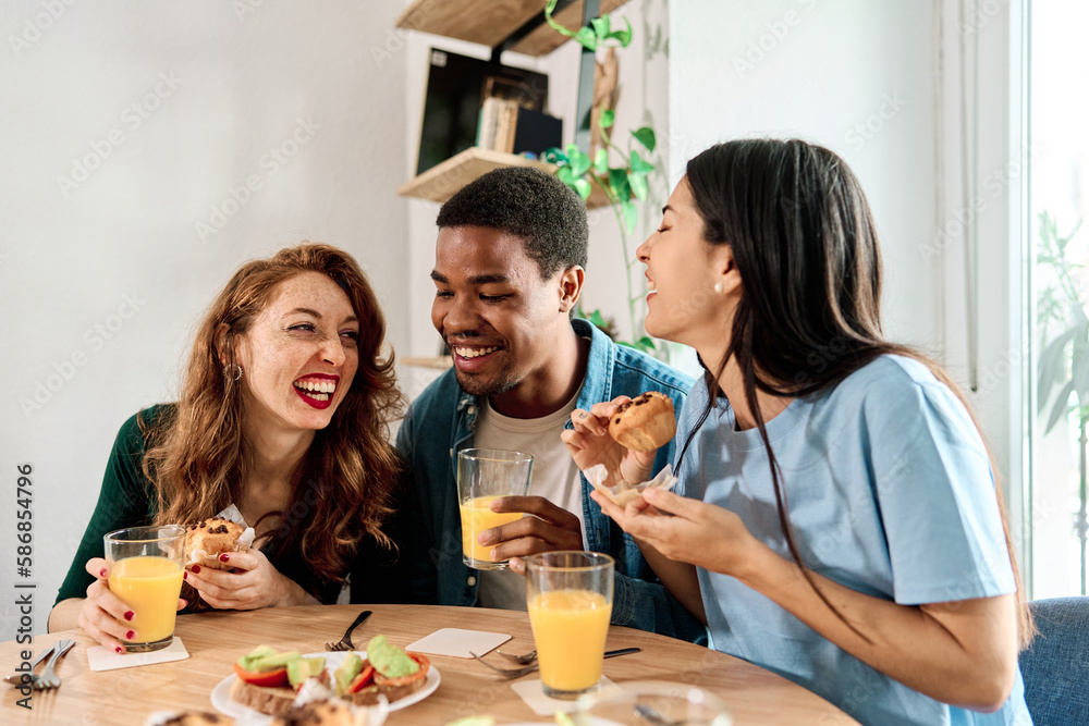 Multiethnic friends eating pastries sitting at home Multiethnic friends eating pastries sitting at home