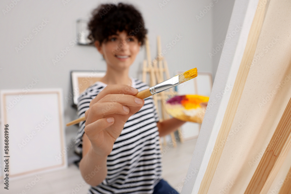 Young woman painting on easel with canvas in studio, selective focus Young woman painting on easel with canvas in studio, selective focus