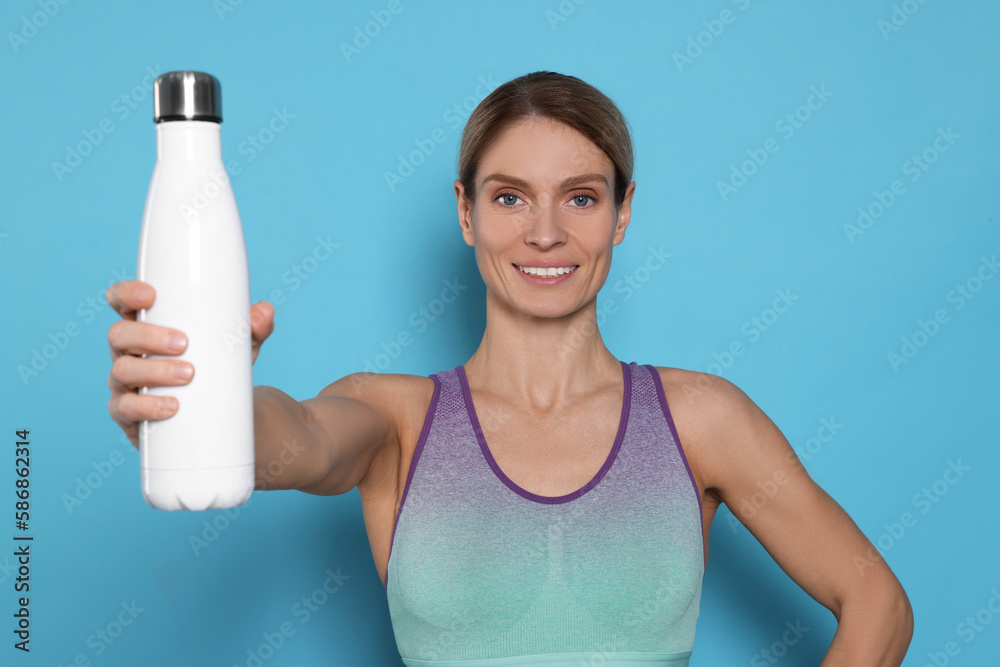 Sportswoman with thermo bottle on light blue background Sportswoman with thermo bottle on light blue background