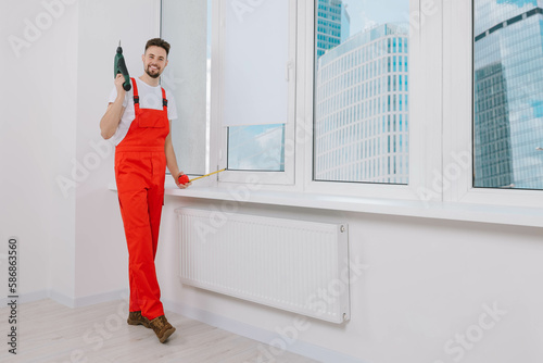 Worker holding tools for installation roller window blinds indoors