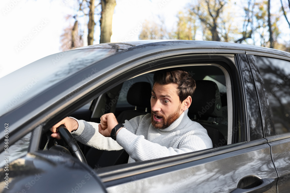 Emotional man checking time on watch in car. Being late concept Emotional man checking time on watch in car. Being late concept