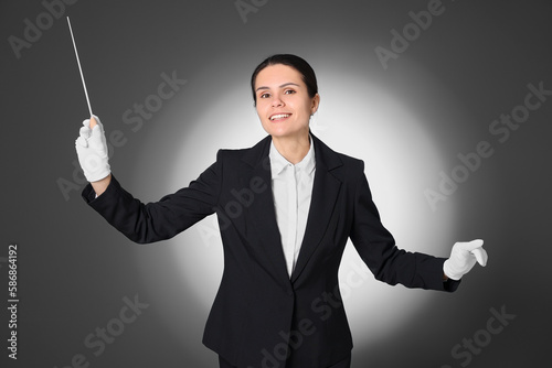 Happy professional conductor with baton on grey background