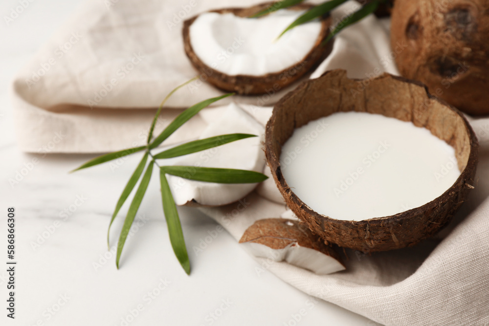 Delicious vegan milk in coconut, leaf and pieces of ripe fruit on white marble table, closeup Delicious vegan milk in coconut, leaf and pieces of ripe fruit on white marble table, closeup