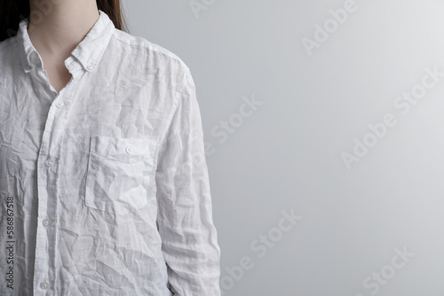Woman wearing wrinkled white blouse on light grey background, closeup. Space for text