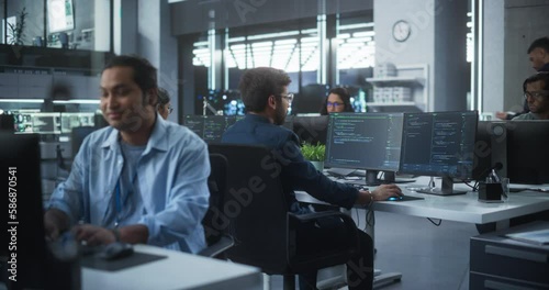 Young Team of South Asian Specialists Working on Computers and Having a Conversation at a Workplace. Two Male Software Developers Discussing a Solution for Their Artificial Intelligence Project photo