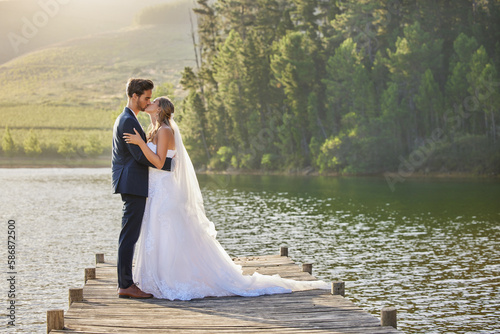 Fotografi Wedding couple, kissing and hug by lake for love affection, intimate or romantic honeymoon getaway in nature