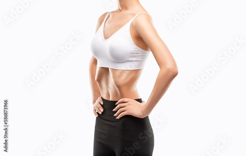 Young woman in black and white sportswear working out her abdominal muscles. Beautiful sporty woman is exercising and doing fitness, belly vacuum.