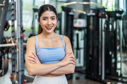 Portrait of Active athlete asian woman in sportswear standing and crossing arms in gym. Sport people using machines exercise for health care then look at camera at fitness club