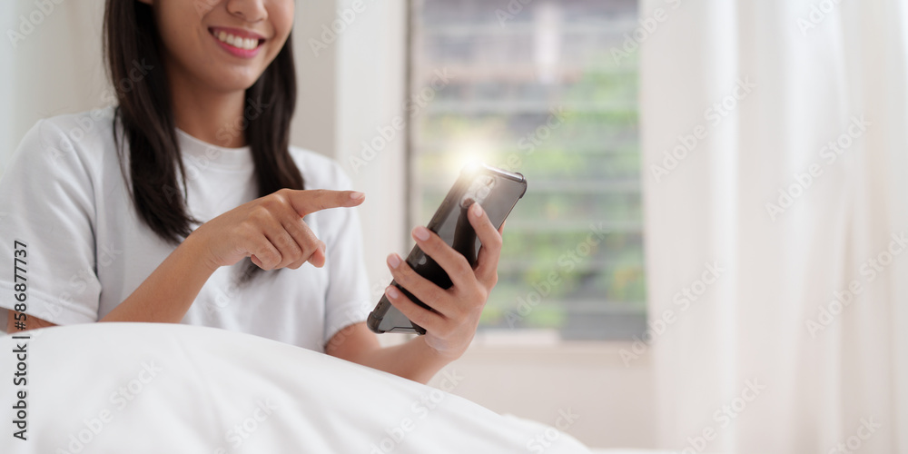 Smiling young asian woman using smart phone in bedroom at home. lifestyle, woman lying on bed Smiling young asian woman using smart phone in bedroom at home. lifestyle, woman lying on bed