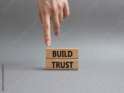 Build trust symbol. Wooden blocks with words Build trust. Beautiful grey background. Businessman hand. Business and Build trust concept. Copy space.
