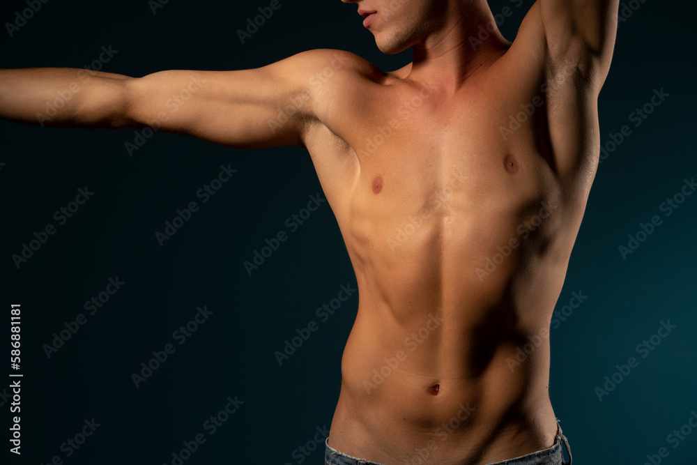 the torso of a young athletic guy. concept: the male body after exercise and diet. men's health: shaved breasts on a dark background