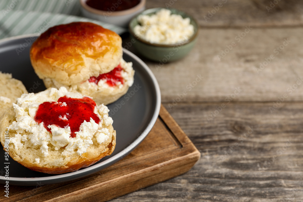 Freshly baked soda water scones with cranberry jam and butter on wooden table, closeup. Space for text