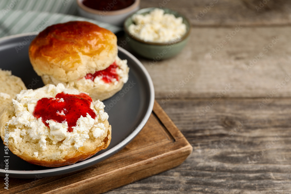 Freshly baked soda water scones with cranberry jam and butter on wooden table, closeup. Space for text Freshly baked soda water scones with cranberry jam and butter on wooden table, closeup. Space for text